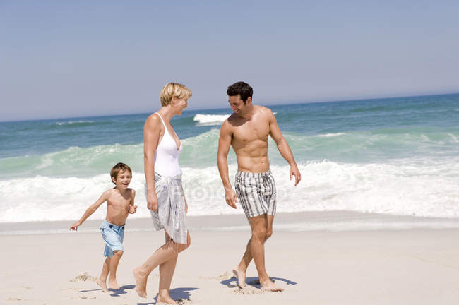 focused_222916910-stock-photo-happy-family-walking-sandy-beach